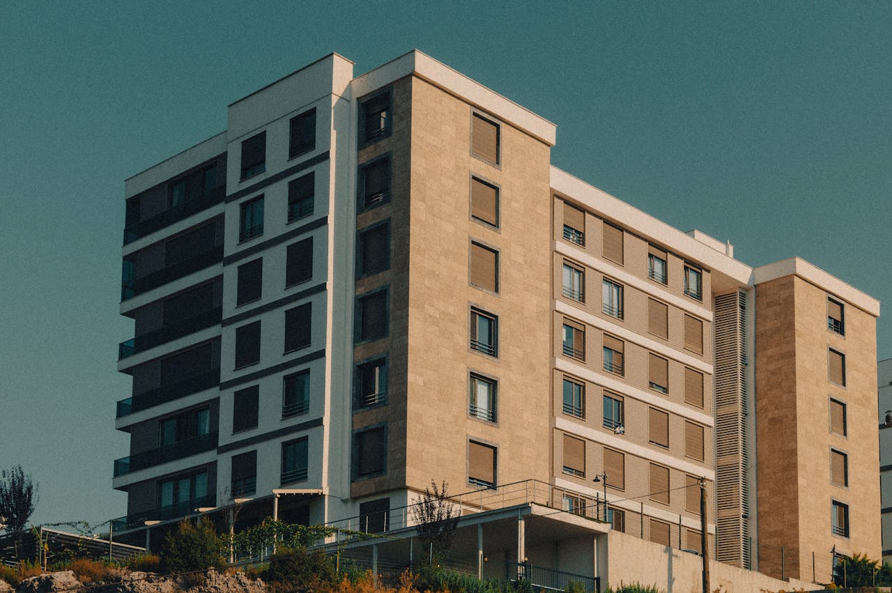 gallery-4 A modern apartment building with beige facade against a clear sky.