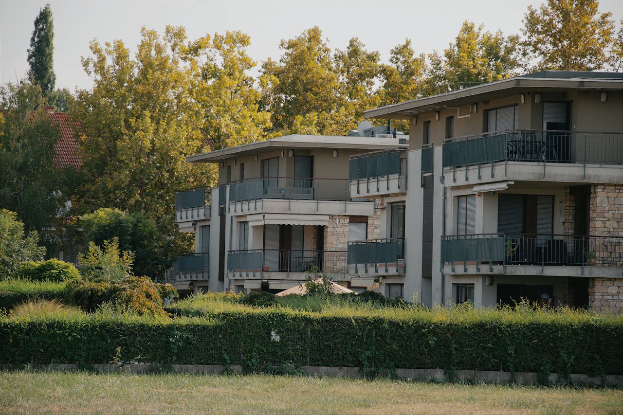 services-02 A scenic view of a modern apartment building surrounded by lush greenery in Hungary.