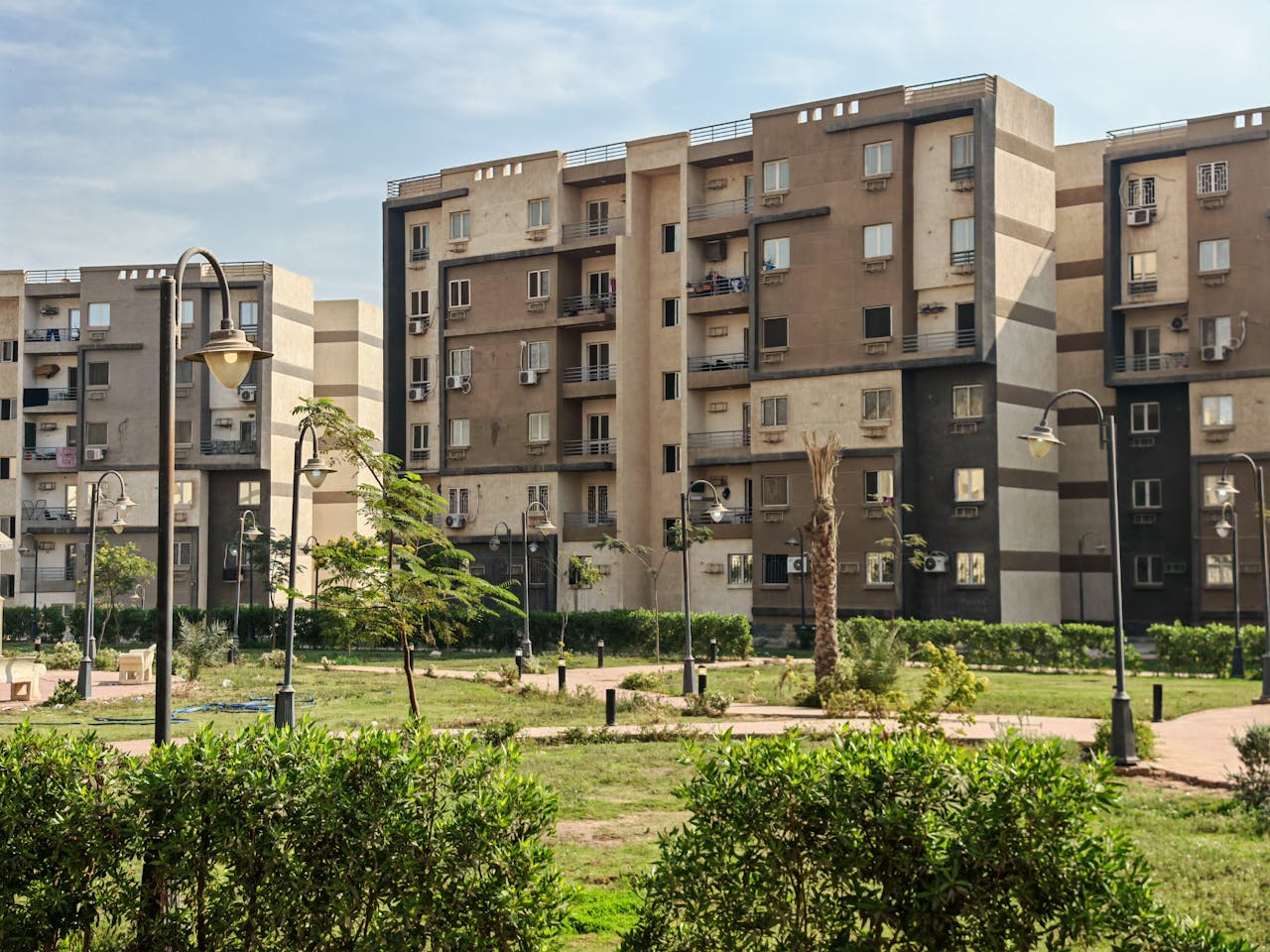 gallery-5 A modern residential building complex with lush greenery and public park.