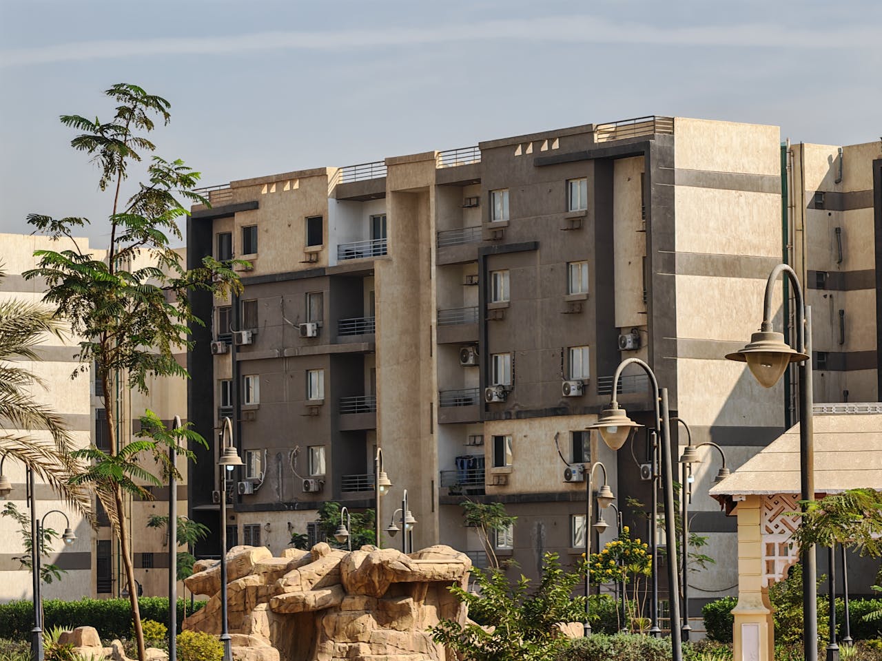gallery-1 Urban residential buildings with landscaped gardens under a clear sky.