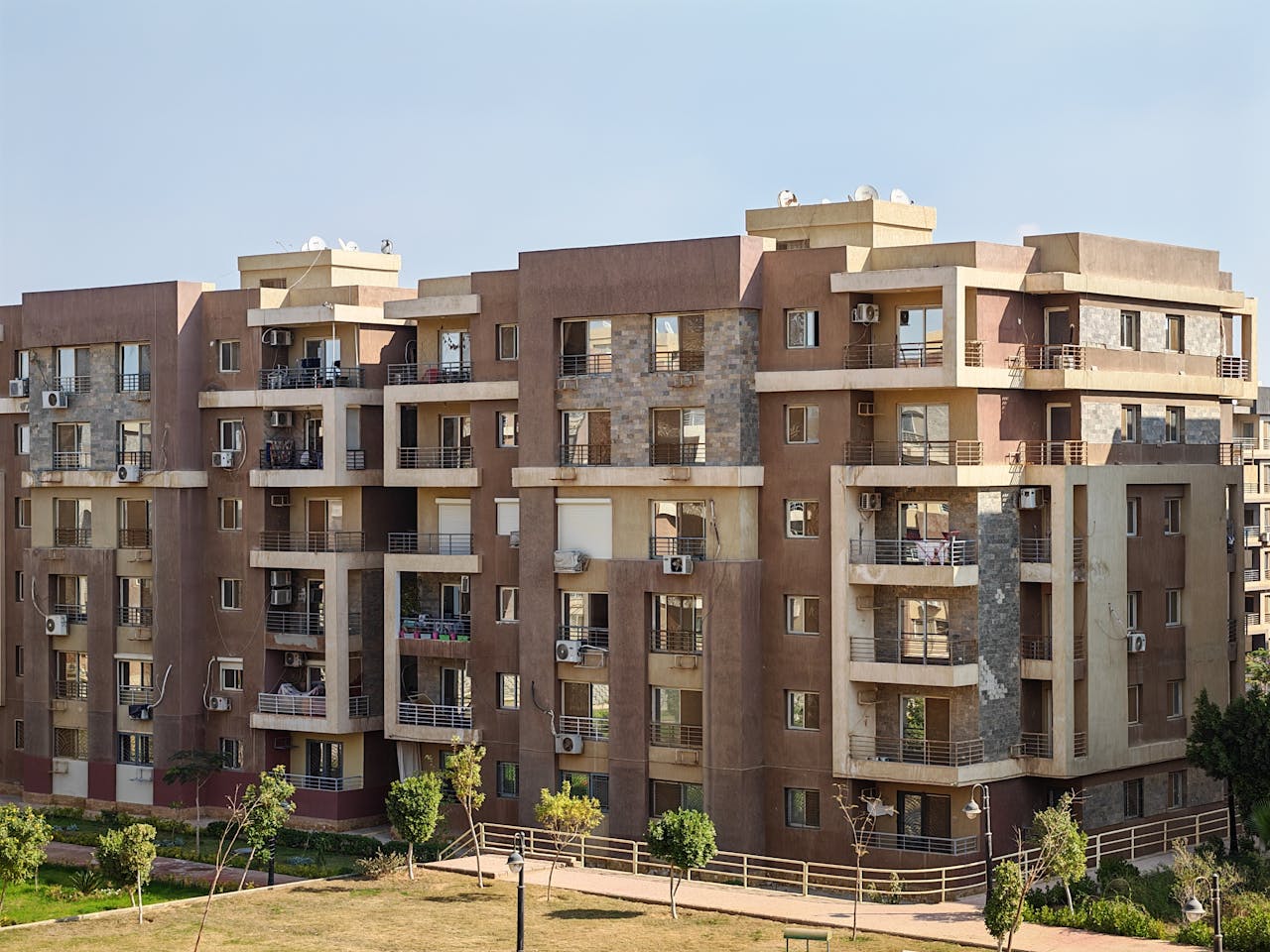 gallery-3 Contemporary multi-story apartment building with balconies in a sunny urban setting.